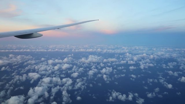 Beautiful view above clouds from airplane perspective with wing in sunset light
