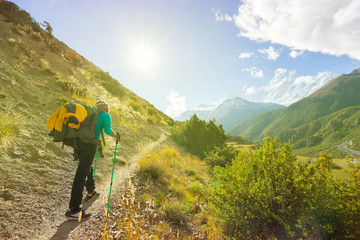 Travel concept. Hiker with backpack and tourist sticks on trekking trail in himalayas mountains. Focus on man