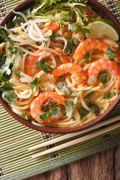 Laksa soup with shrimps, noodles, sprouts and coriander in a bowl close-up. vertical top view