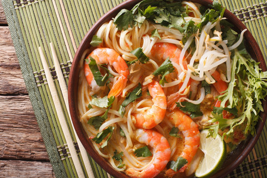 Laksa soup with shrimps, noodles, sprouts and coriander in a bowl close-up. Horizontal top view