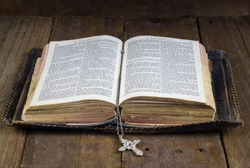 Old Holy Bible on rustic wood table with cross book mark