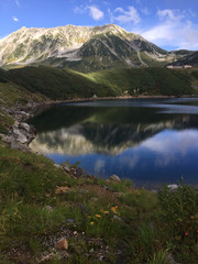 Mount Tateyama mirrored in the Mikurigaike pond's blue surface at Murodo, Japan, as part of the Alpine Route. September, 2016.