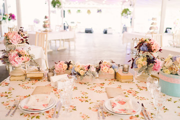 Table setting at country wedding reception, wedding floral decoration, wrapped books and candles. Overhead view.