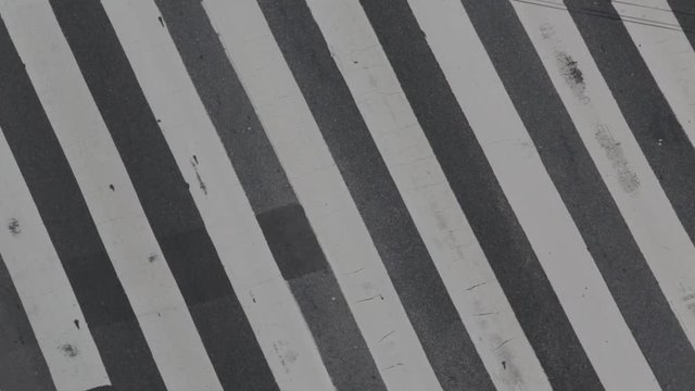 Aerial detail, close up of zebra line of a road street. Traffic flow, pulse, movement. Taxi, motorcycle, vehicle.