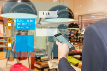 Chatbot concept. Man using  smart phone with virtual chatbopt user interface and greeting message on blur menwear shop background.