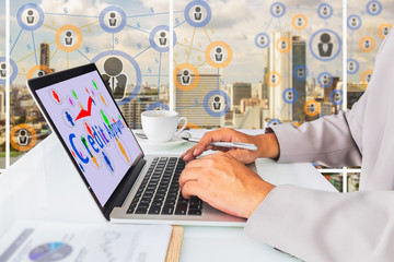 P2P lending concept.  Business man using laptop computer with P2P lending icons and credit approved message on screen, cup of coffee against social media connection on city background.