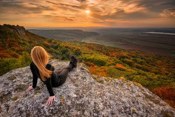 Sunset from the top /
A woman on the top of a rock enjoys the view of sunset over an autumn forest