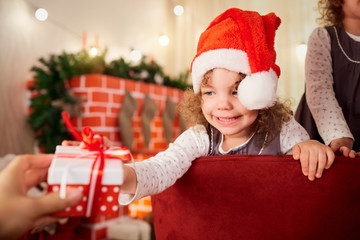 Children in Christmas. Little girl in the hat of Santa Claus pul