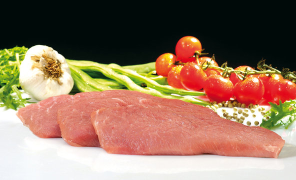 Schweine Schnitzel mit Gem&uuml;se Tomaten auf Glasplatte