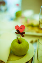 Paper heart with guest name stands in the green apple