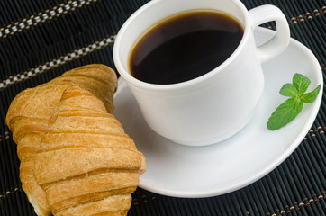 fresh cup of hot black coffee with croissants