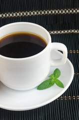 fresh cup of hot black coffee with mint leaves
