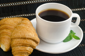 fresh cup of hot black coffee with croissants
