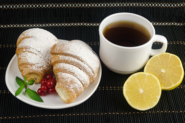 fresh cup of hot black coffee with croissants and lemon