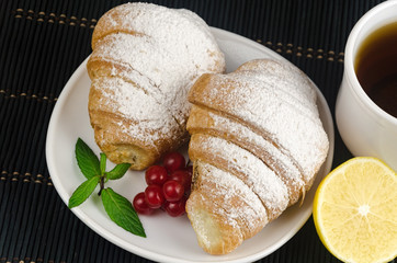 fresh cup of hot black coffee with croissants and lemon