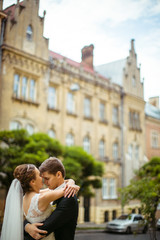 Old high building hangs over the wedding couple hugging on the s