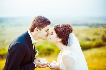 Bride and groom touch each other noses while posing with white c