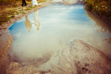 Wedding couple reflects in the pool over blue sky
