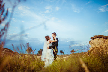 Deep blye sky hangs over the wedding couple standing in the high