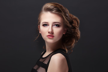 Fashion beauty portrait of a beautiful young girl with bulk haircut on one side isolated on a black background.