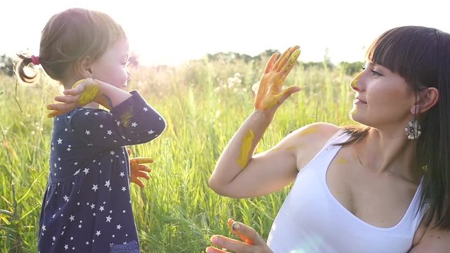 Mother and child daughter high five with colored painted hands on nature