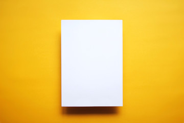 Empty white paper sheet isolated yellow background