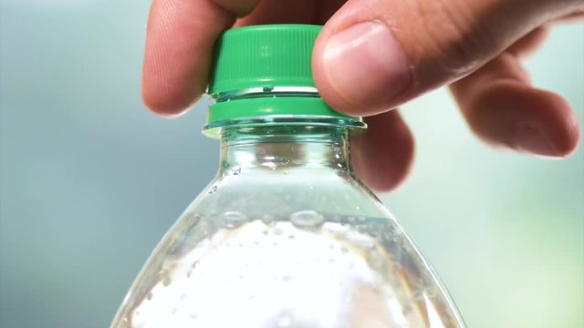 Hands opening a bottle of fresh mineral water - in slow motion fullHD video. Close-up of plastic bottle cool soda water. 