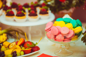 Green, yellow and pink macaroons stand in the glass bowl