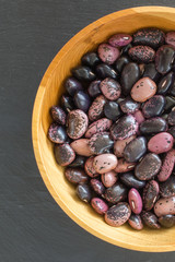 rain purple beans of different colors on a black background. vegetarian raw food. food color background in dark colors
