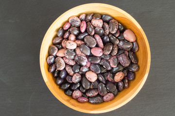 rain purple beans of different colors on a black background. vegetarian raw food. food color background in dark colors