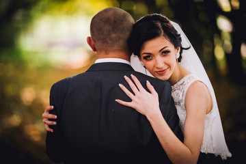 Kissing bride and groom in their wedding day near autumn tree