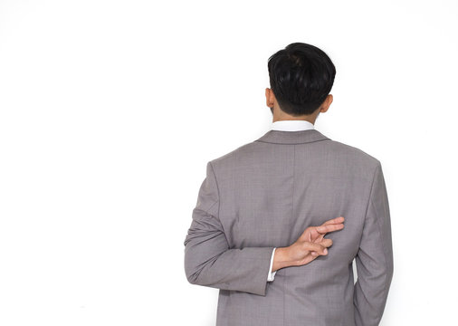 Businessman with fingers crossed behind his back with copy space.