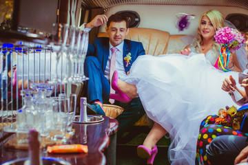 Stylish blonde bride puts her leg in pink shoe on groom's knee