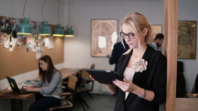 4k. closeup young beautiful blonde businesswoman uses a touchscreen tablet in the modern startup office.