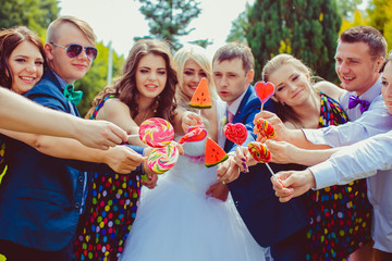 Newlyweds and friends reach oyt their hands with sugar candies