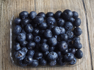 Blueberries in the container on wood backgroung