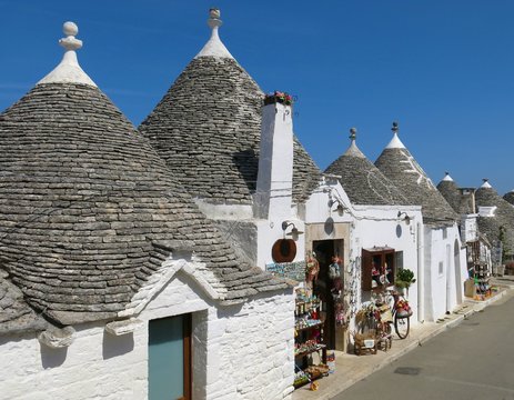 Row of trulli (plural of trullo) in Alberobello, Italy. These stone structures with conical rooftops are specific to the Itria Valley in Apulia.