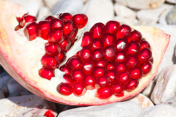 Part of pomegranate fruit on light stone background. Organic fresh product