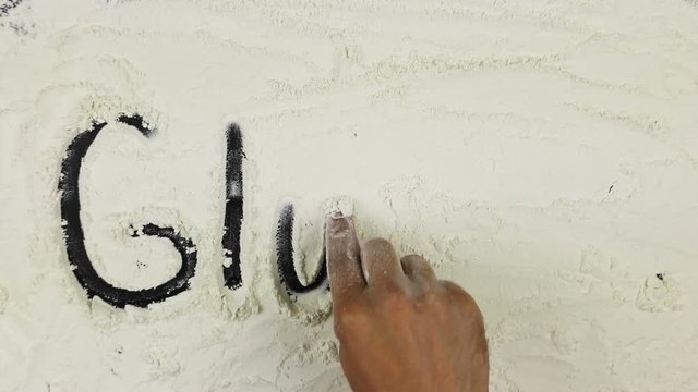 Young man writes a word gluten strikethrough on white flour
