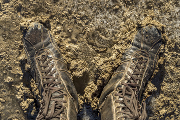 Schnürstiefel versinken im nassen Erdboden