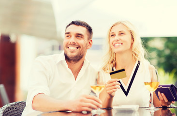 happy couple with bank card and bill at restaurant
