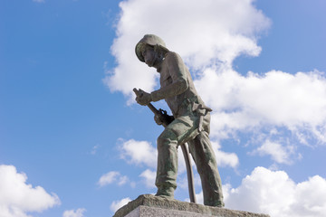Firefighter statue with blue sky and clouds in the background