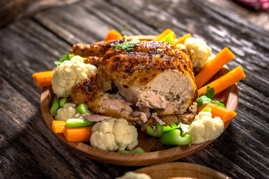 Whole roasted chicken with vegetables on wooden background