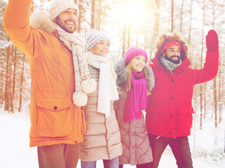 group of friends waving hands in winter forest