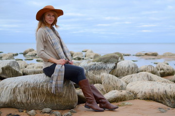 Young beautiful woman in a hat walks on the sea