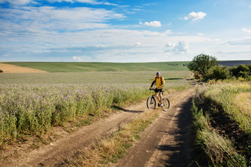 Cyclist riding a bike on off road to the sunset