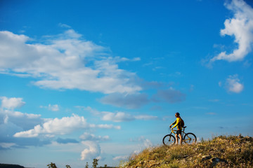 Cyclist riding a bike on off road to the sunset