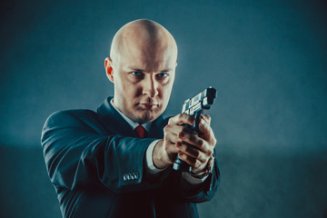 Bald man in business suit with the gun.