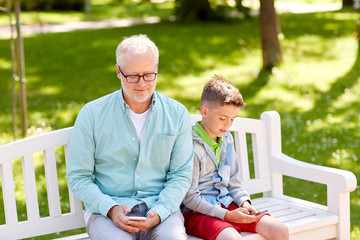 old man and boy with smartphones at summer park