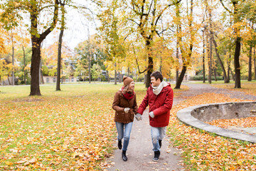 happy young couple running in autumn park